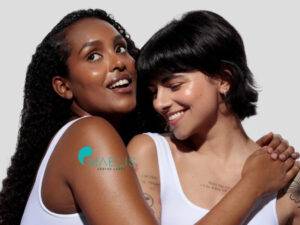 Deux femmes souriantes, l'une de peau noire et l'autre de blanche, chez Maelis Centre laser
