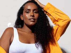 Femme à la peau foncée vêtu d'une chemise orange et un top blanc